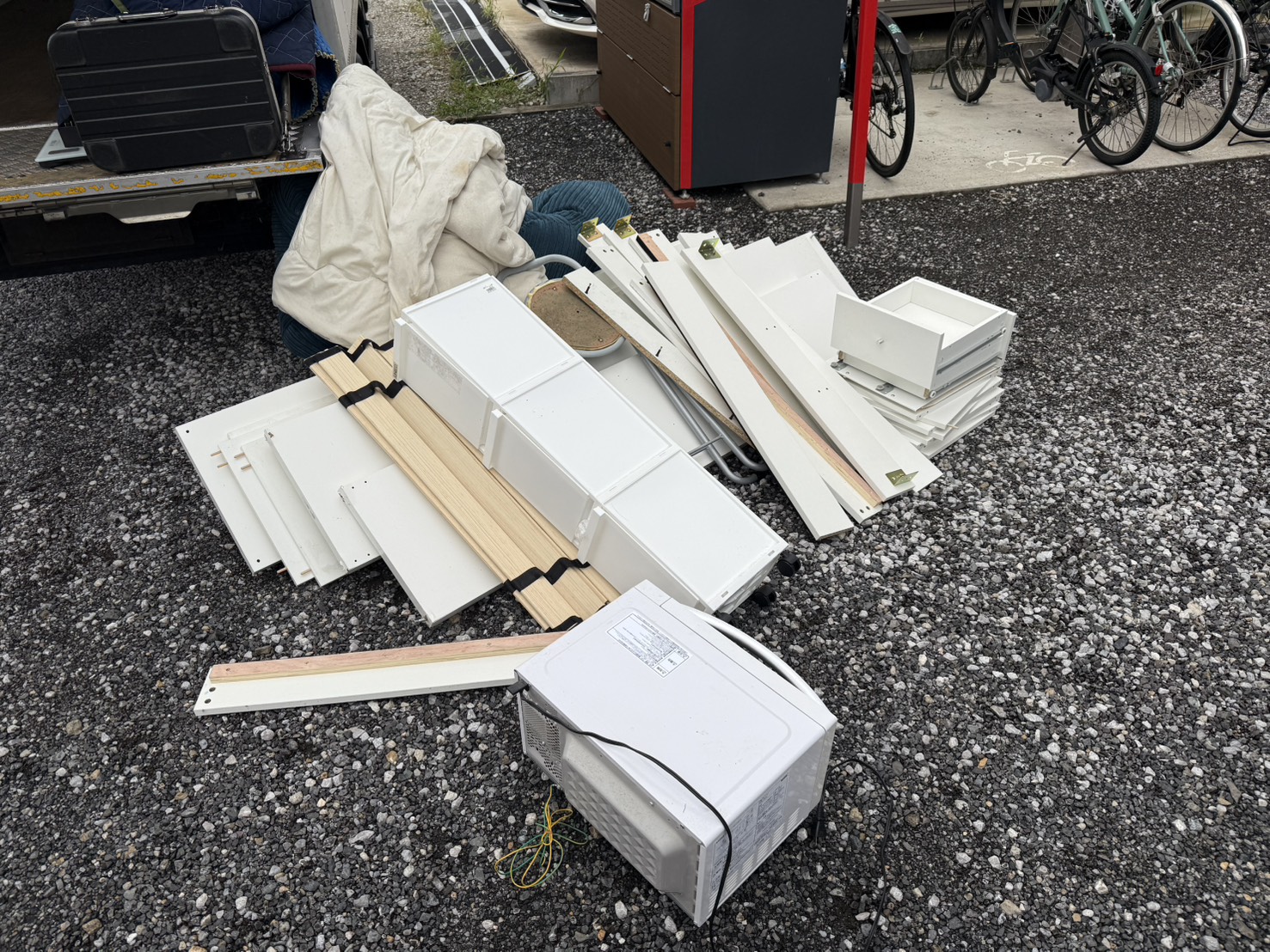 千葉県八街市での不用品回収の作業写真（ベッドフレーム、電子レンジ、ソファ、布団、棚）